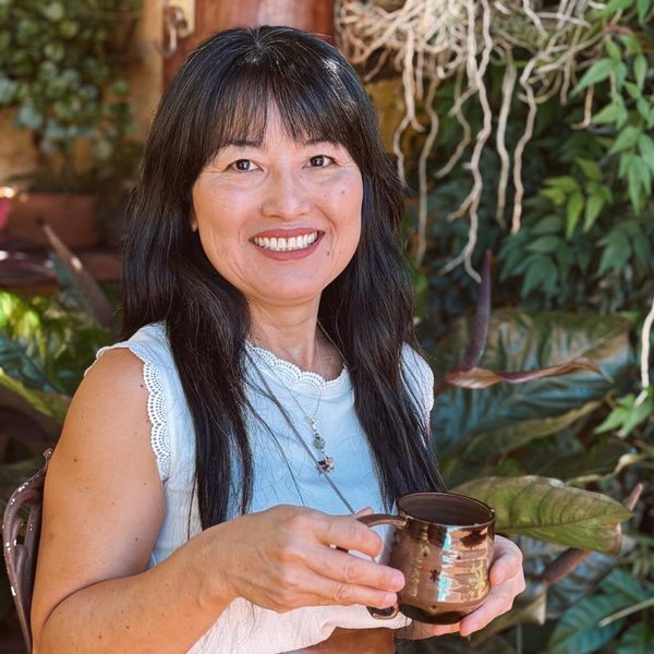 Cláudia Yumi Matsubara, terapeuta, sorrindo em ambiente natural